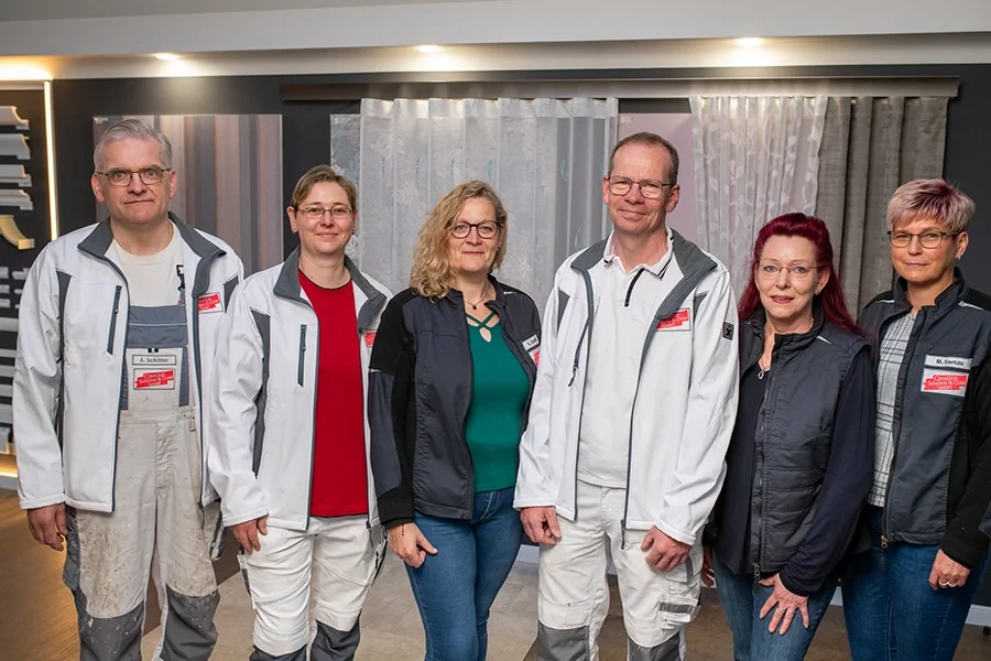 Teambild für Kontaktseite – Mitarbeiter in Arbeitskleidung stehen zusammen