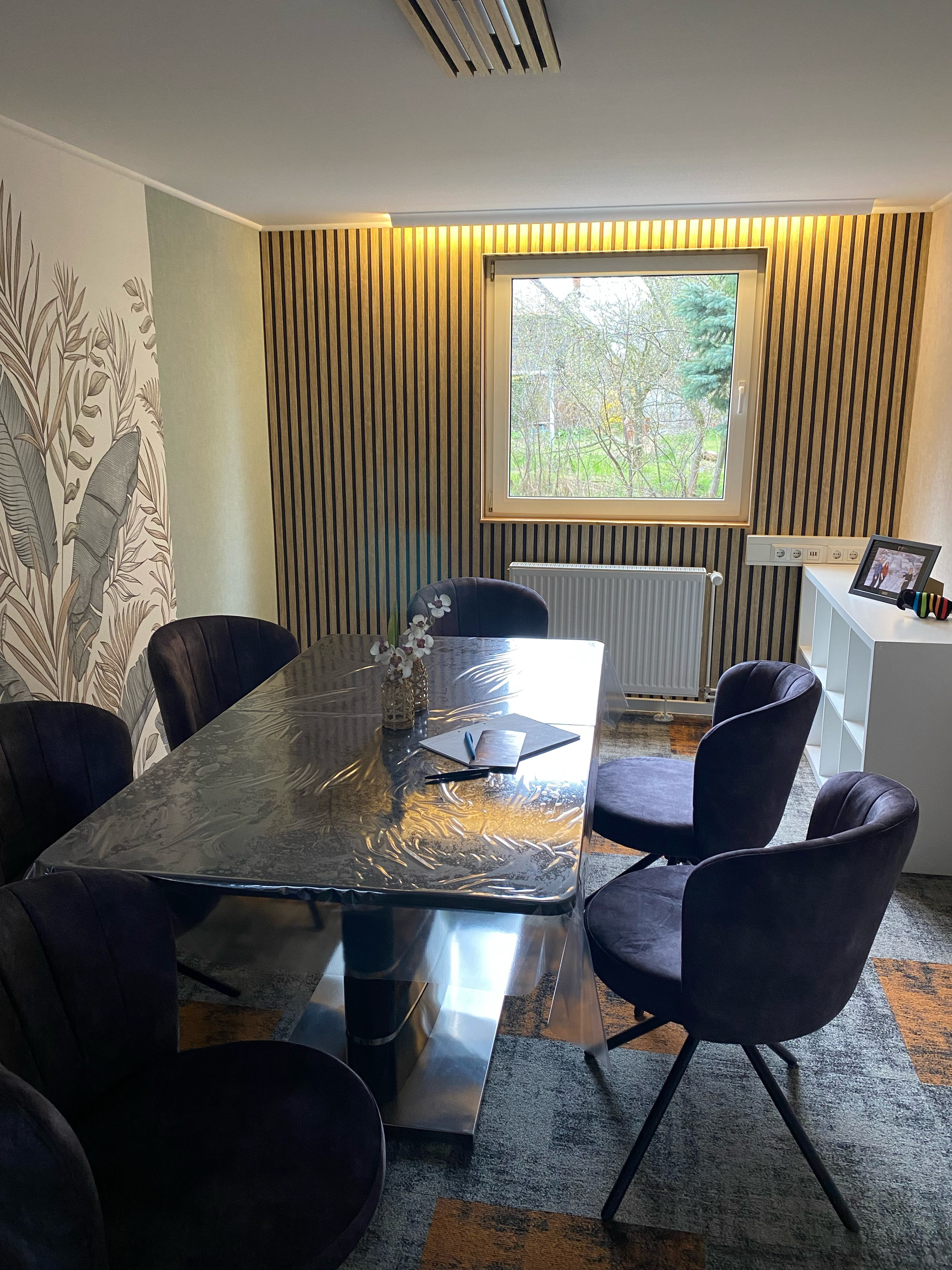 Vergleich zwischen Tapeten und Akustikelementen an den Wänden eines modernen Besprechungsraums mit Tisch und Stühlen