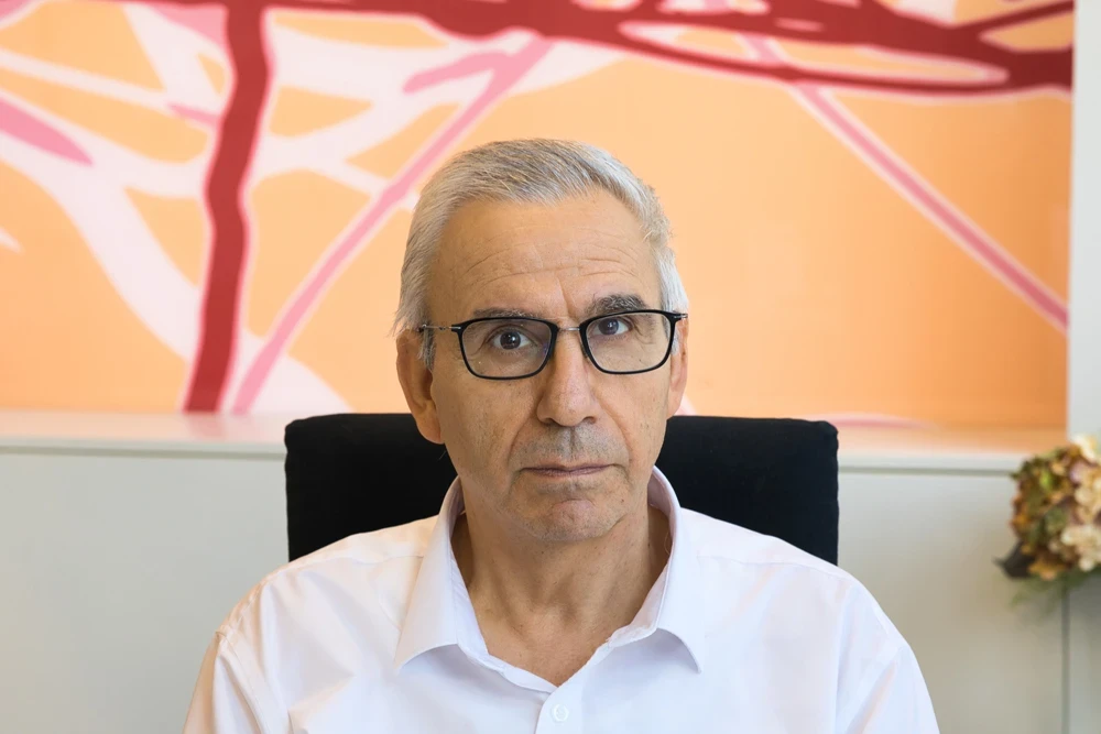 Dr. Khader sitzt im Büro vor einem modernen Hintergrund