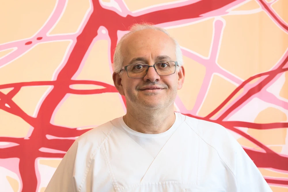 Herr Hasan in weißer Kleidung vor buntem Hintergrund