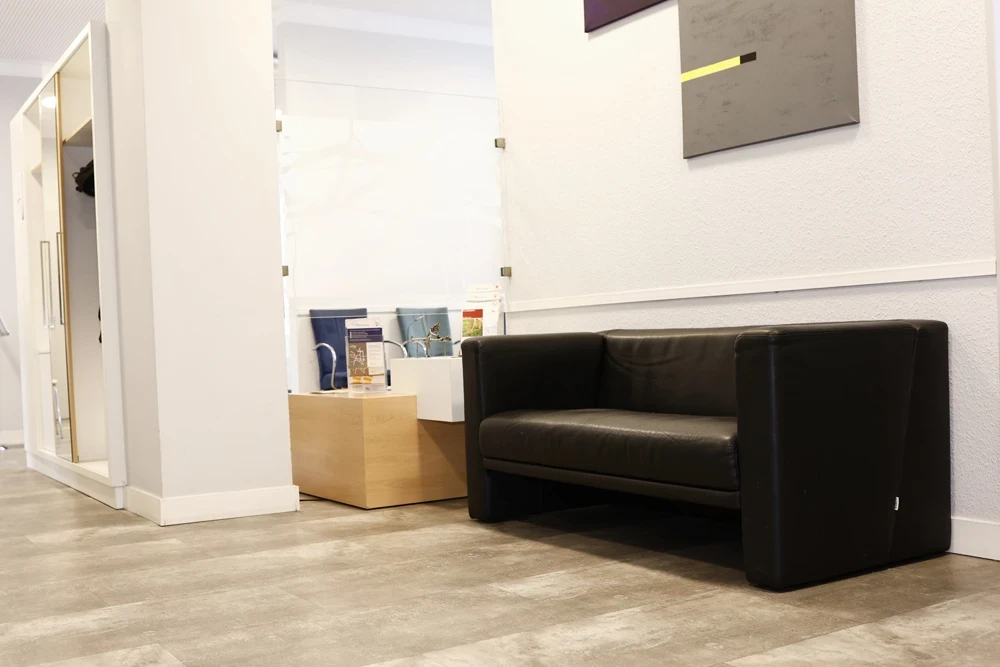 Wartebereich im Gefäßzentrum Bielefeld mit schwarzem Ledersofa und Infomaterial