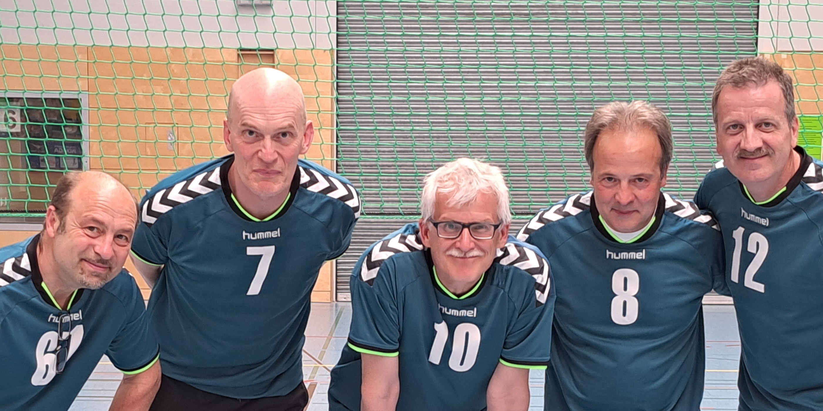 Drei Handballspieler in blauen Trikots in einer Sporthalle