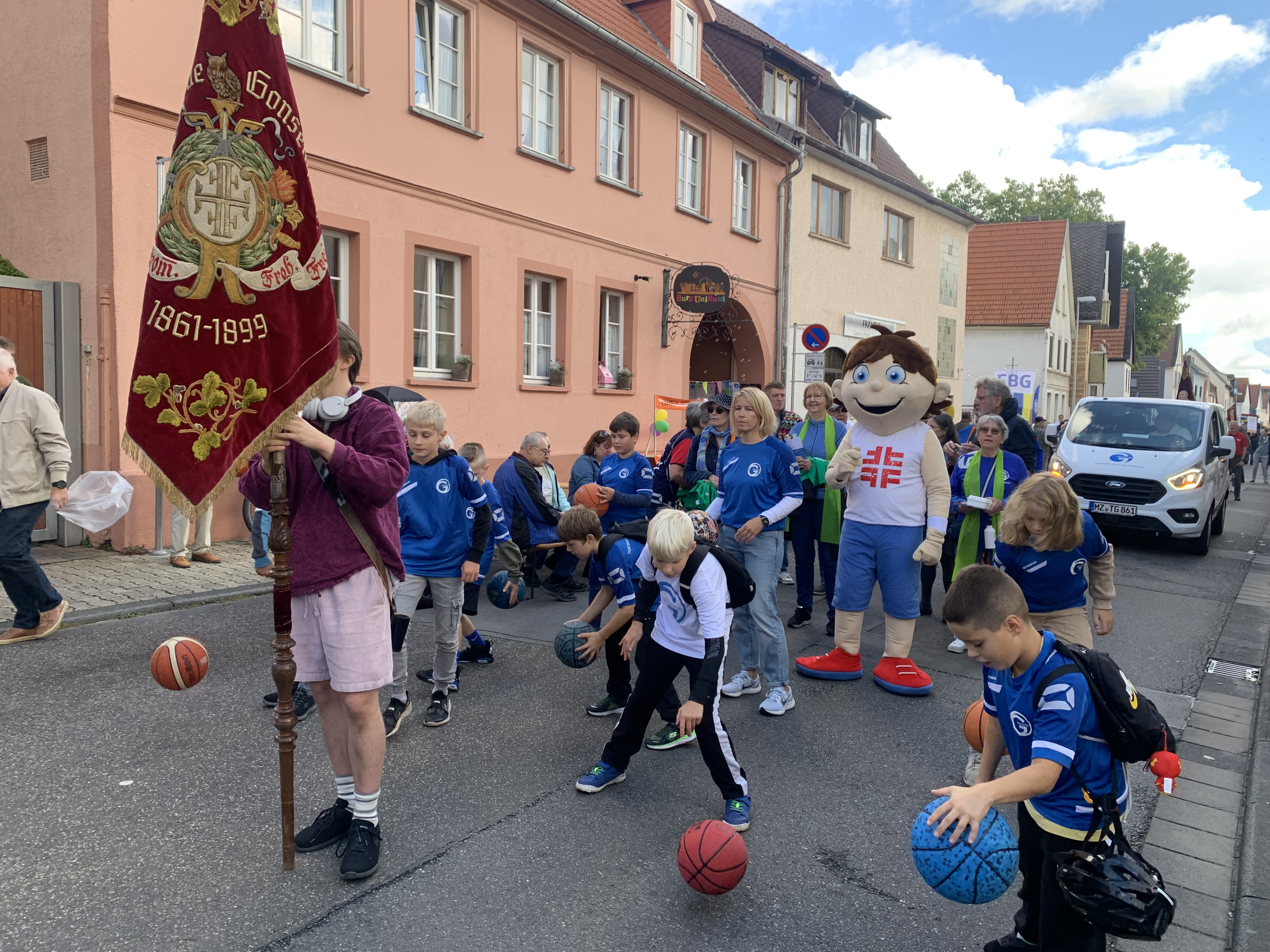 Kinder und Erwachsene in blauen Trikots mit Basketballen bei einem Festumzug in einer deutschen Stadt