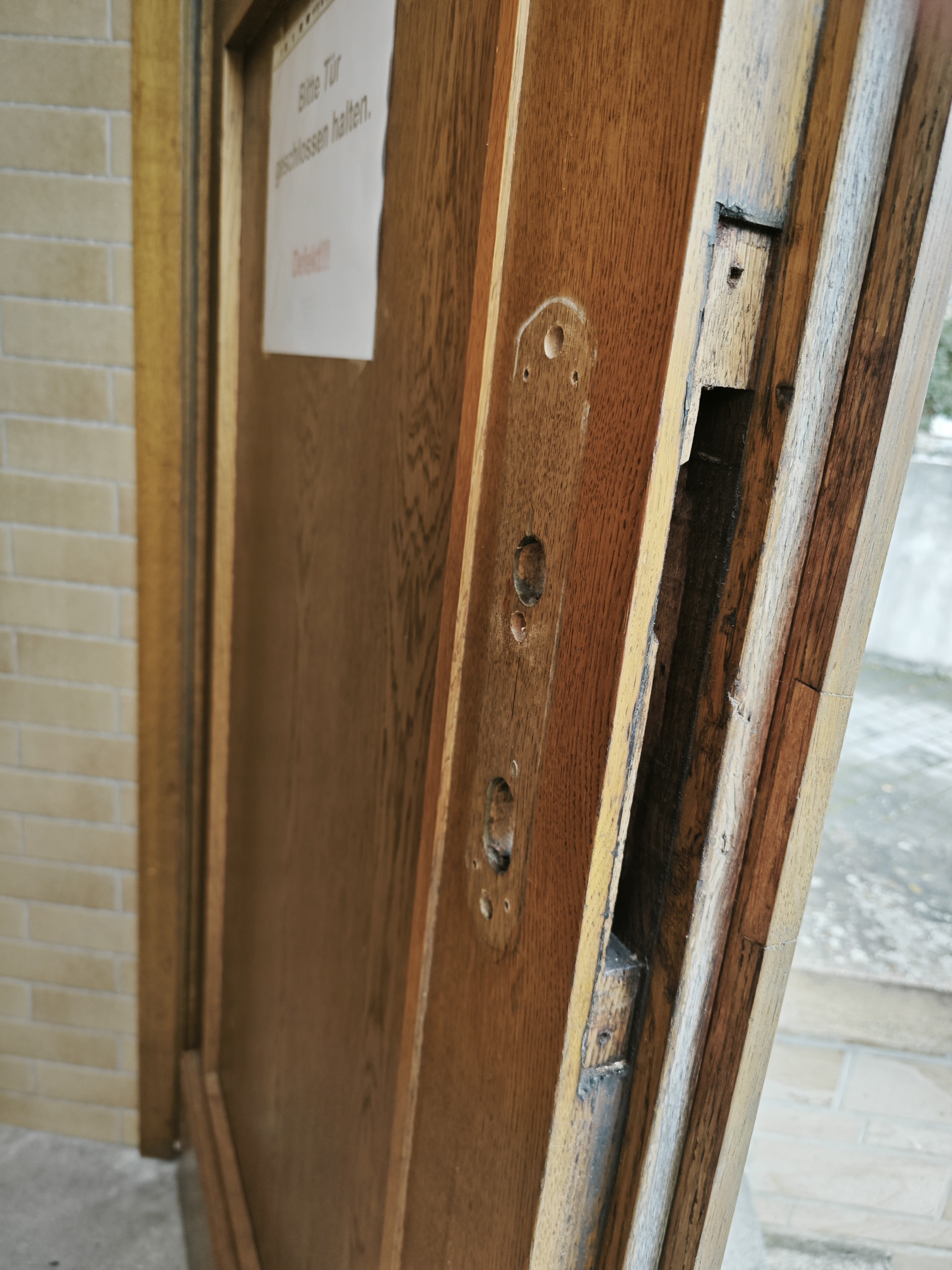 Nahaufnahme einer aufgebrochenen Holztür mit beschädigtem Türrahmen