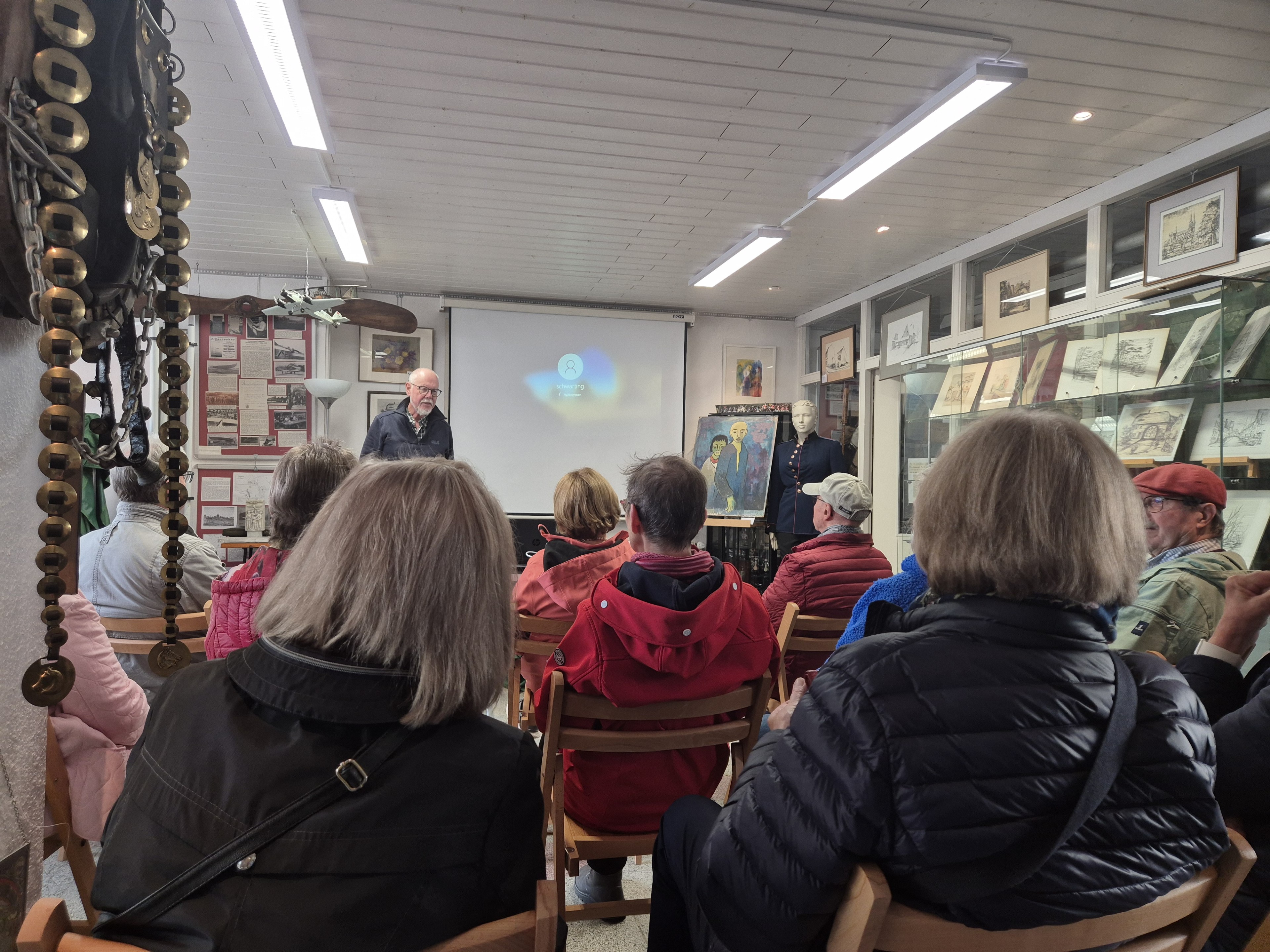 Vortrag mit Publikum in einem kleinen Museum mit Ausstellungsstücken und Präsentation