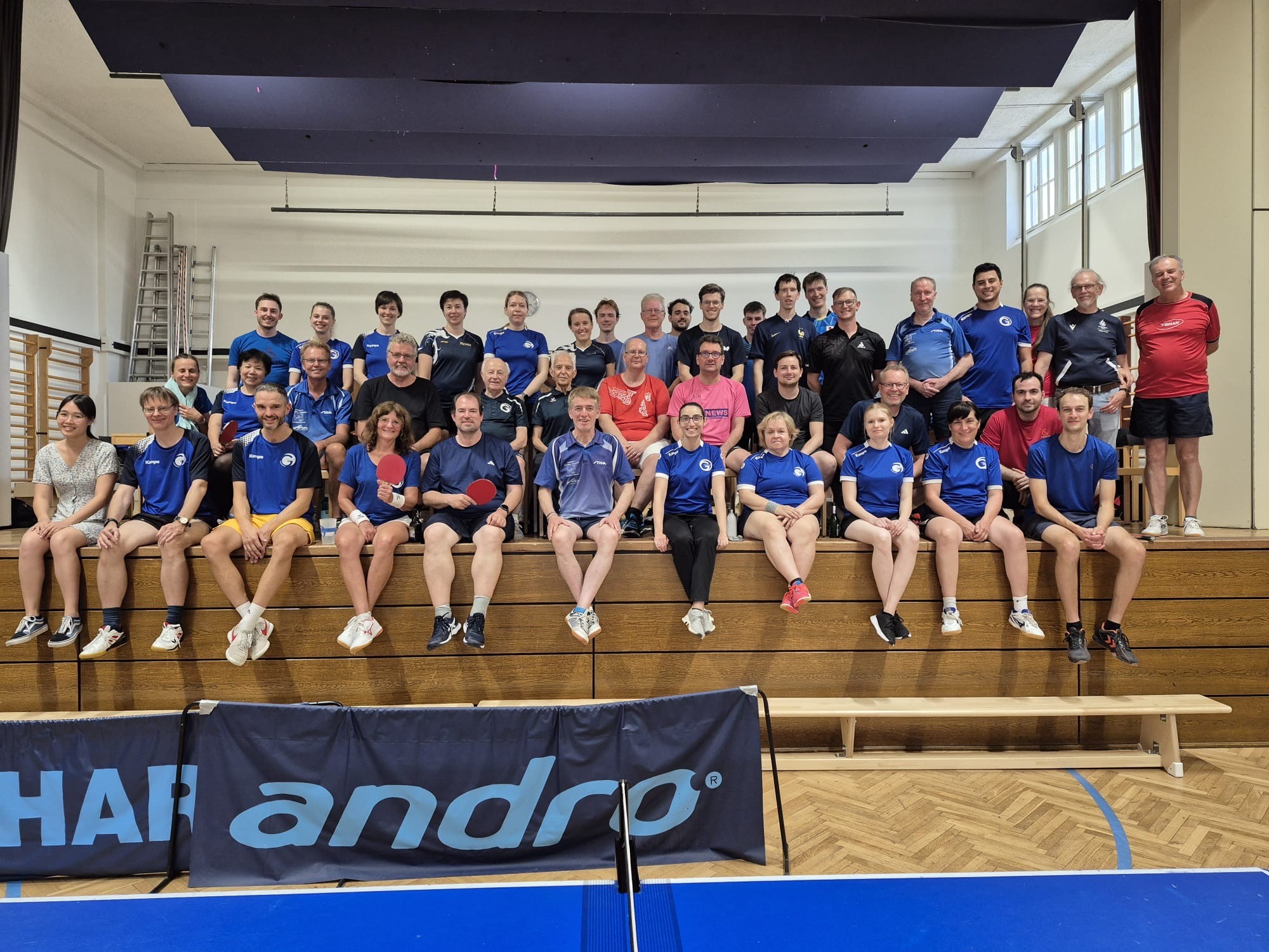 Gruppenfoto von Tischtennisspielern in einer Sporthalle mit Andro-Bande
