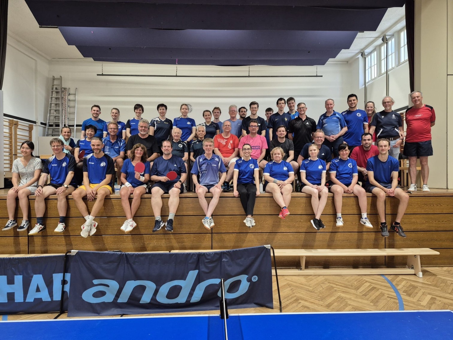 Gruppenfoto von Tischtennisspielern in einer Sporthalle mit Andro-Bande