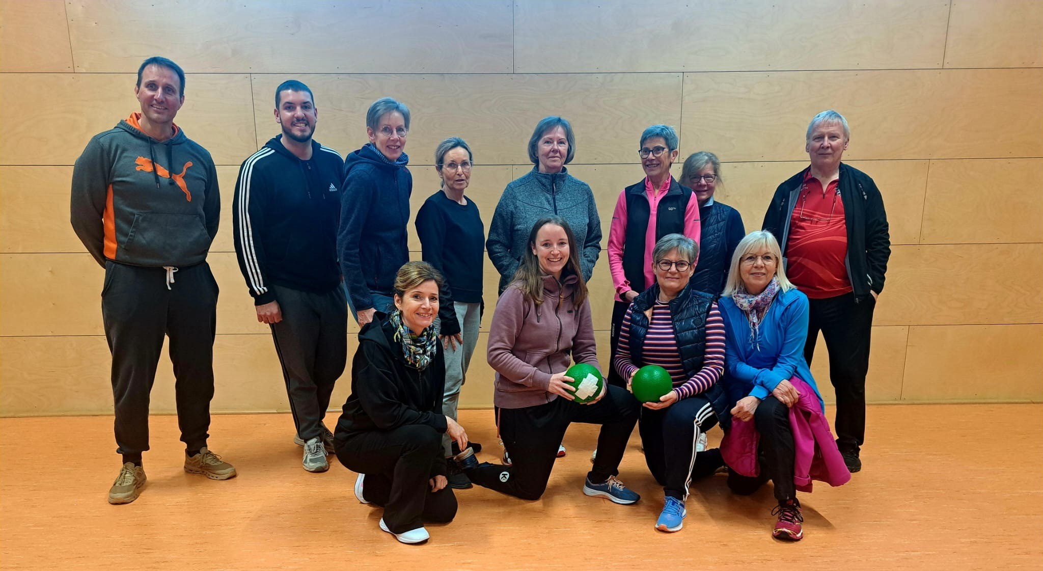 Gruppe von Menschen beim Sport in einer Halle mit Gymnastikbällen