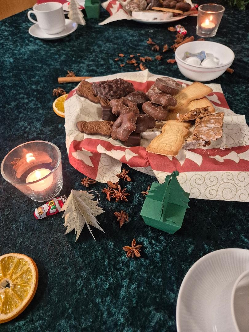 Adventstisch mit Kerze, Weihnachtsgebäck, Spekulatius, Dominosteinen und dekorativen Elementen zur Adventszeit