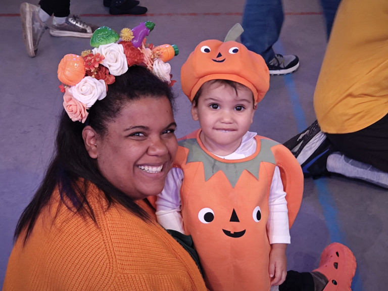 Kind und Erwachsene im Kürbis-Kostüm bei einer Halloween- oder Karnevalsveranstaltung