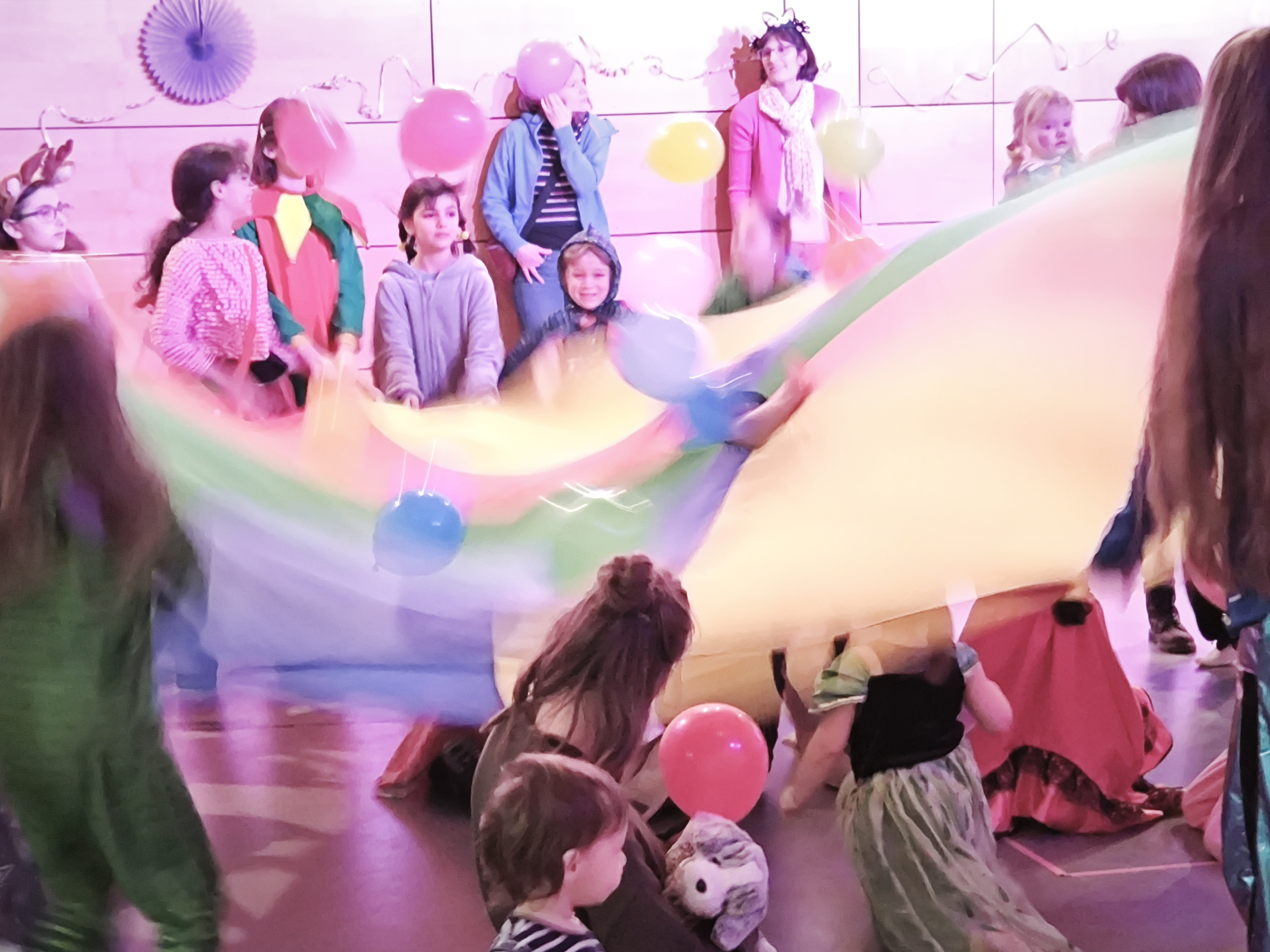 Kinder spielen mit buntem Schwungtuch und Luftballons auf einer Geburtstagsfeier