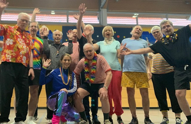 Gruppe von Menschen in bunter Verkleidung bei einer fröhlichen Veranstaltung in einer Halle