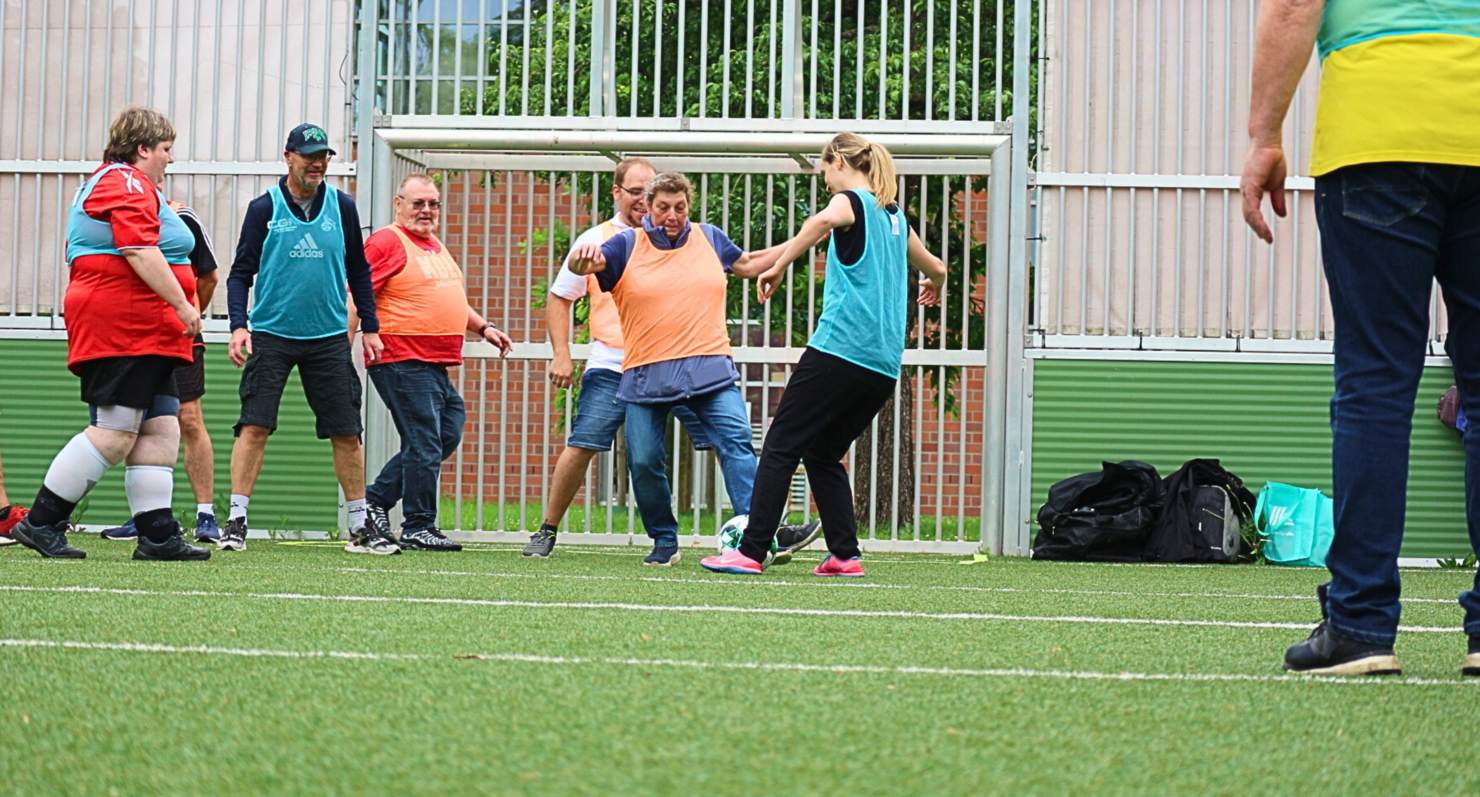 Menschen spielen Fußball auf einem Kunstrasenplatz mit farbigen Leibchen