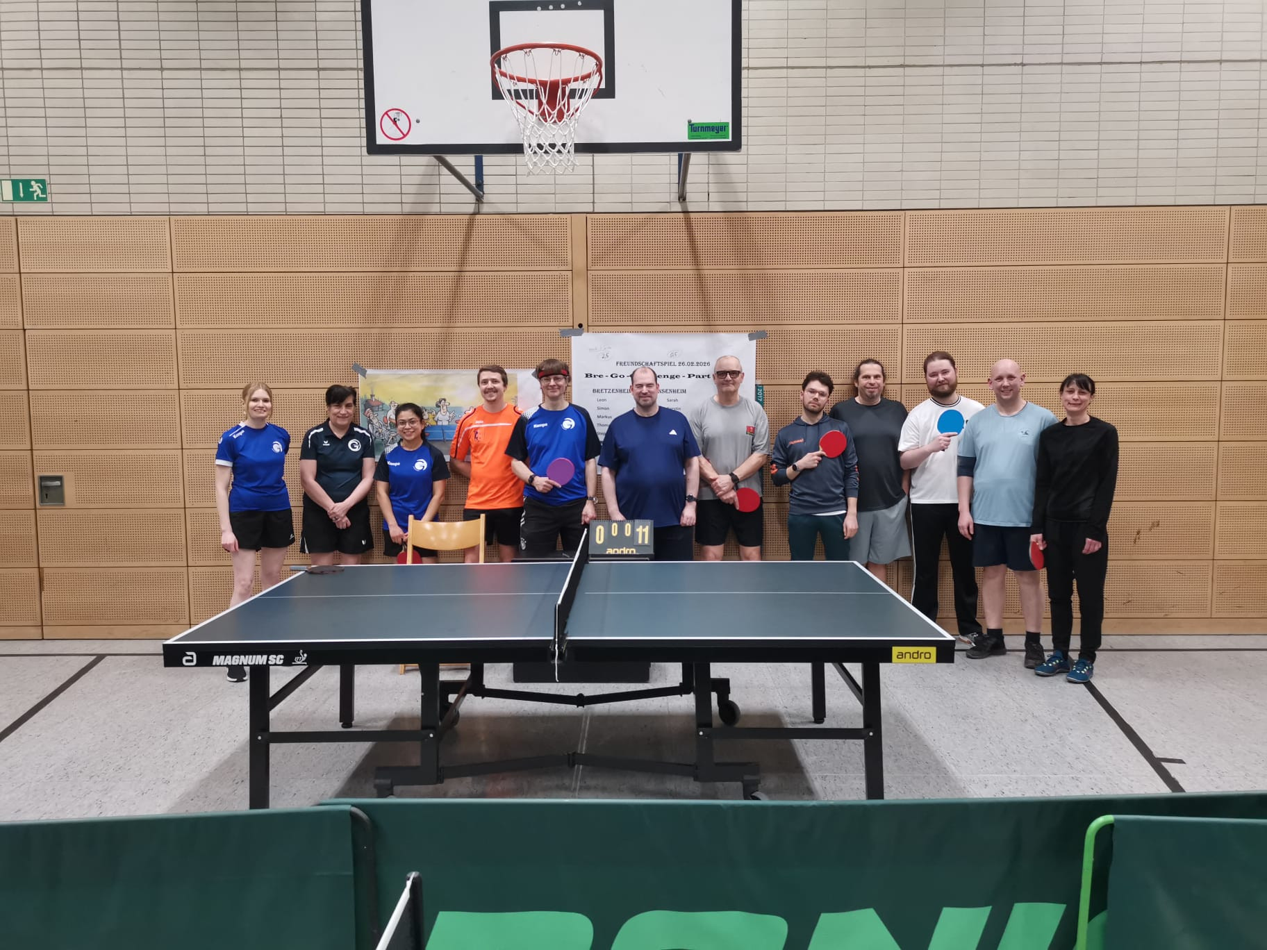 Gruppenfoto von Tischtennisspielern in einer Sporthalle vor einer Tischtennisplatte