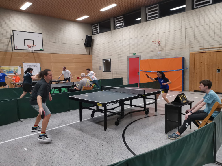 Tischtennis Einzelspiel in einer Sporthalle mit mehreren Spielern an verschiedenen Tischen