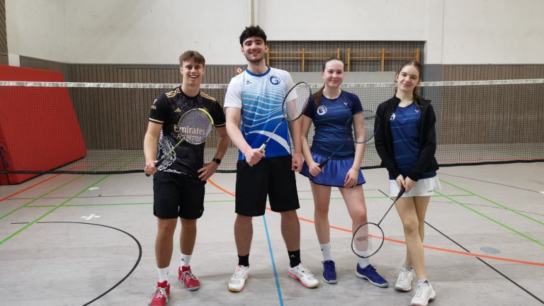 Badmintonspieler beim Blockspieltag in der Sporthalle mit Schlägern vor dem Netz