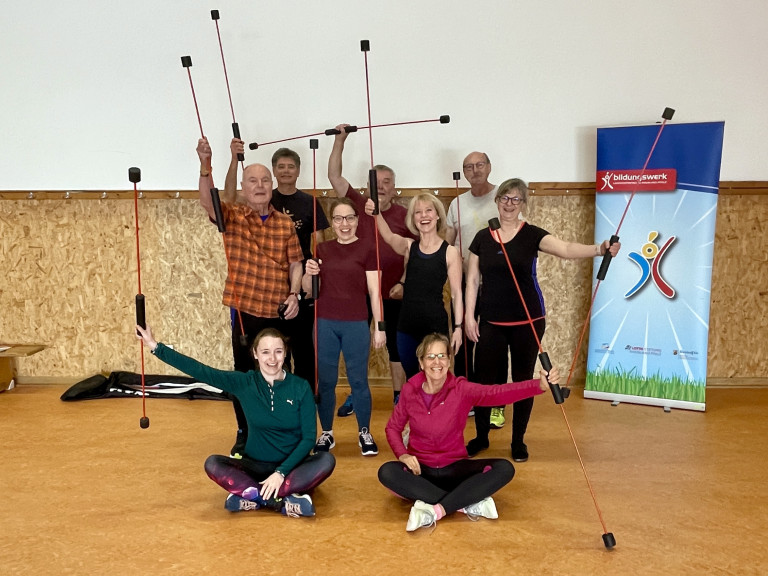 Fitnesskurs mit Flexi-Bar Stäben in der Sporthalle – Gruppenfoto Gruppe von Erwachsenen beim Fitnesskurs mit Flexi-Bar Stäben in einer Sporthalle