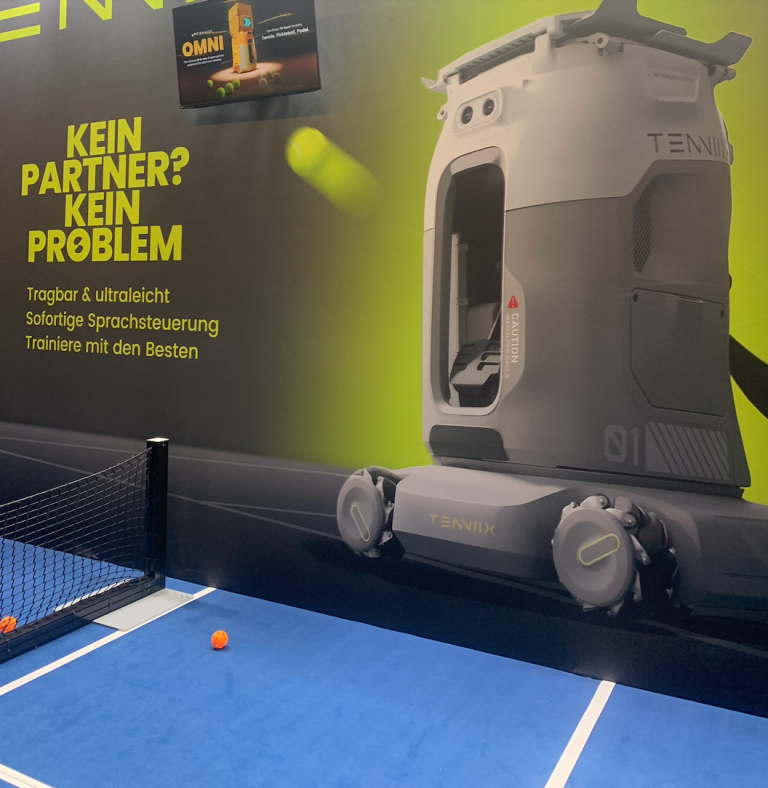 Tennix Ballmaschine auf Tennisplatz mit Werbeplakat, tragbar und sprachgesteuert, aufgenommen am 18.04.2026
