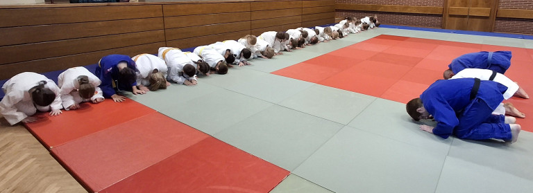Kinder verbeugen sich in Judokleidung auf einer Judomatte, vermutlich bei einem Judo-Training oder -Turnier