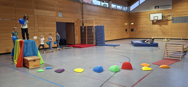 Kinder spielen in einer Turnhalle mit bunten Balancier-Elementen, aufgenommen am 18.04.2026