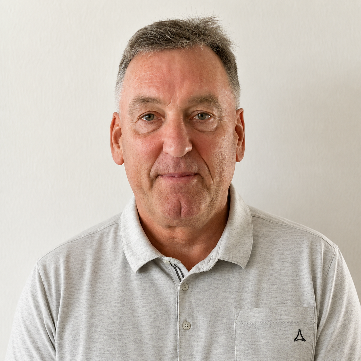 Porträt eines Mannes mit grauem Poloshirt vor hellem Hintergrund
