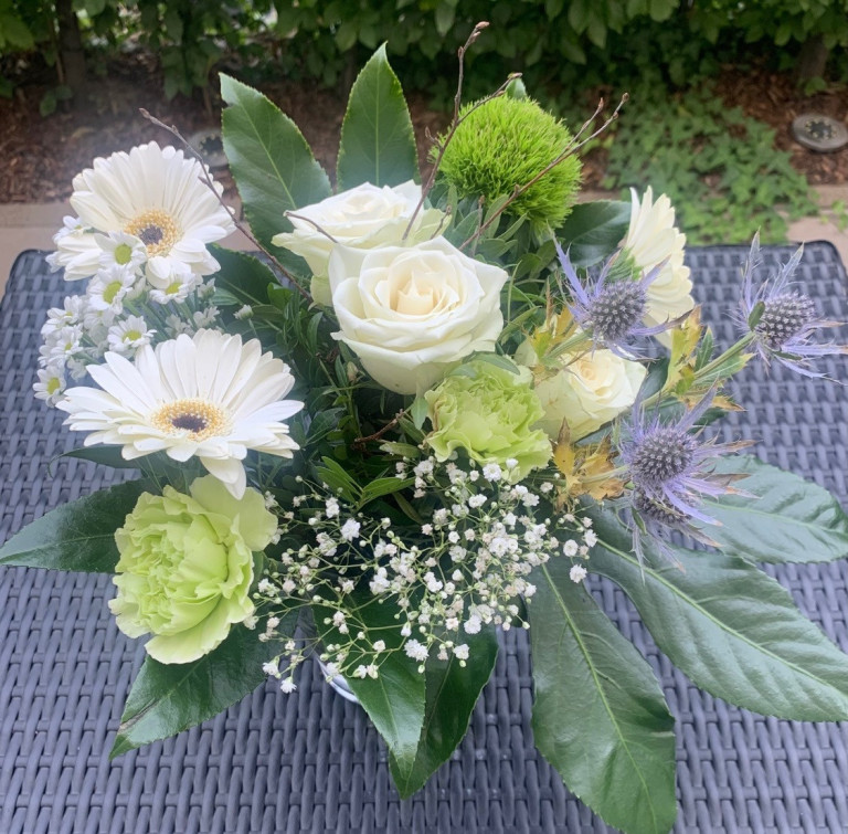 Dankeschön-Blumenstrauß mit weißen Blumen als Geschenk oder Aufmerksamkeit Dankeschön Blumenstrauß mit weißen Rosen, Gerbera und Schleierkraut auf Gartentisch