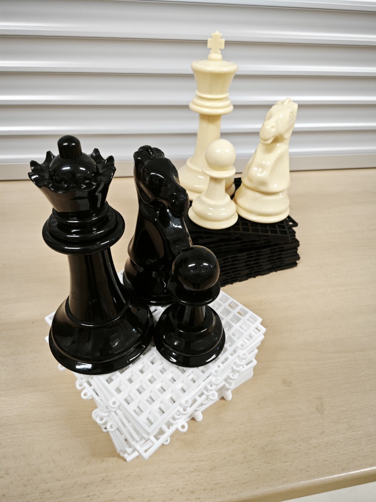 Große Schachfiguren aus Kunststoff auf einem Tisch, schwarze und weiße Figuren nebeneinander
