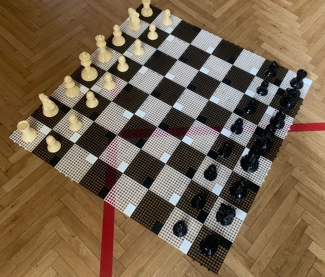 Schachbrett mit Schachfiguren auf einem Holzfußboden, Startaufstellung