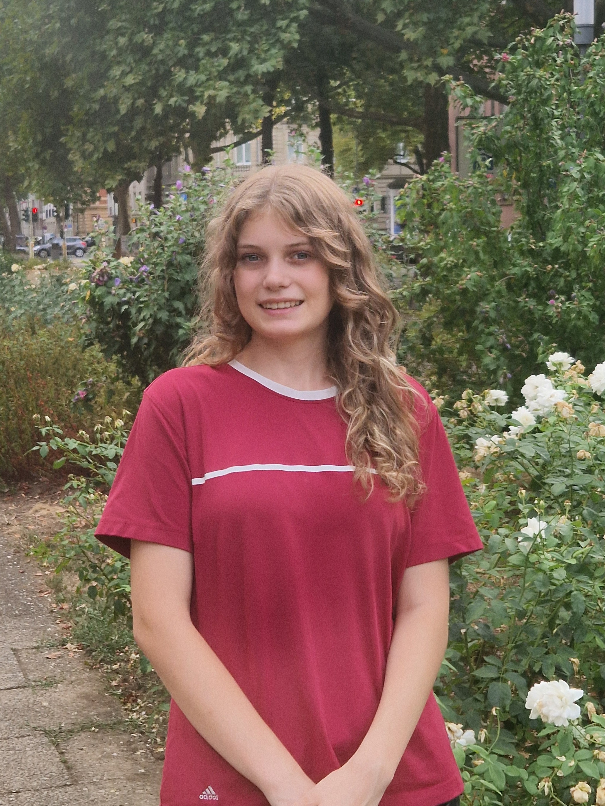 Nele Scheffe im Garten, Porträtfoto einer jungen Frau mit lockigem Haar