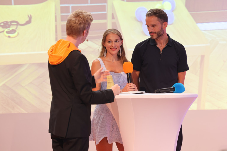 Veranstaltung am 20.08.2026 – Gesprächsrunde mit drei Personen und Mikrofonen an einem Stehtisch Drei Personen bei einer Veranstaltung am 20.08.2026 an einem Stehtisch mit Mikrofonen