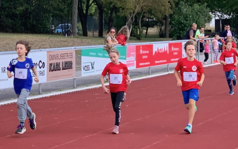 Kinder laufen auf der Laufbahn bei einem Leichtathletik-Wettbewerb, img-0028.jpeg Kinder beim Leichtathletik-Lauf auf einer roten Laufbahn, img-0028.jpeg