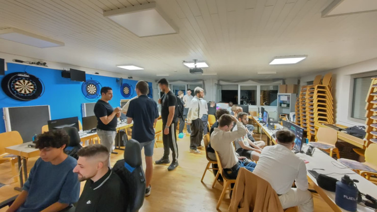 LAN-Party oder Gaming-Event mit mehreren Teilnehmern an Computern und Dartboards Gruppe junger Menschen bei einer LAN-Party oder Gaming-Event in einem Raum mit Computern und Dartboards