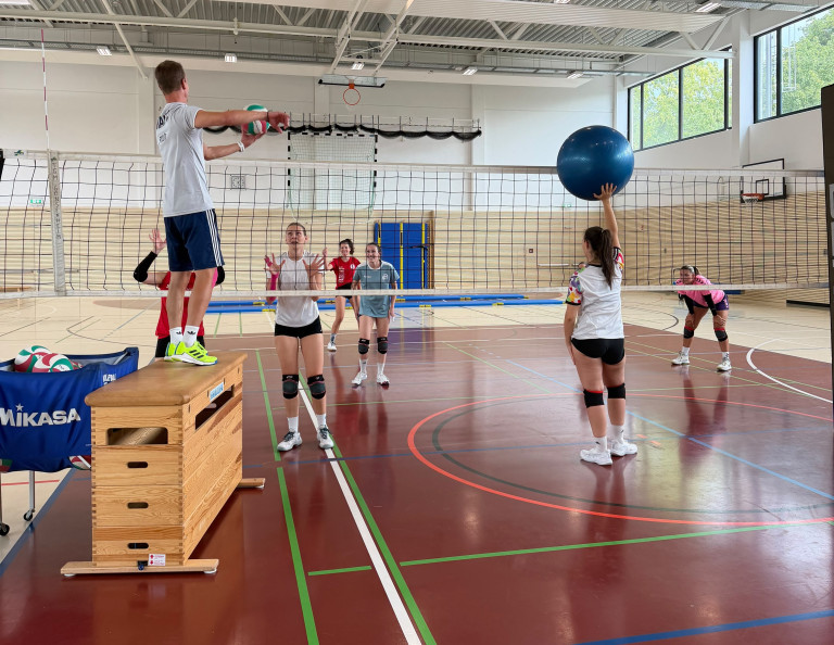 Volleyball-Training in der Sporthalle mit Jugendlichen und Trainer, verschiedene Trainingsübungen am Netz