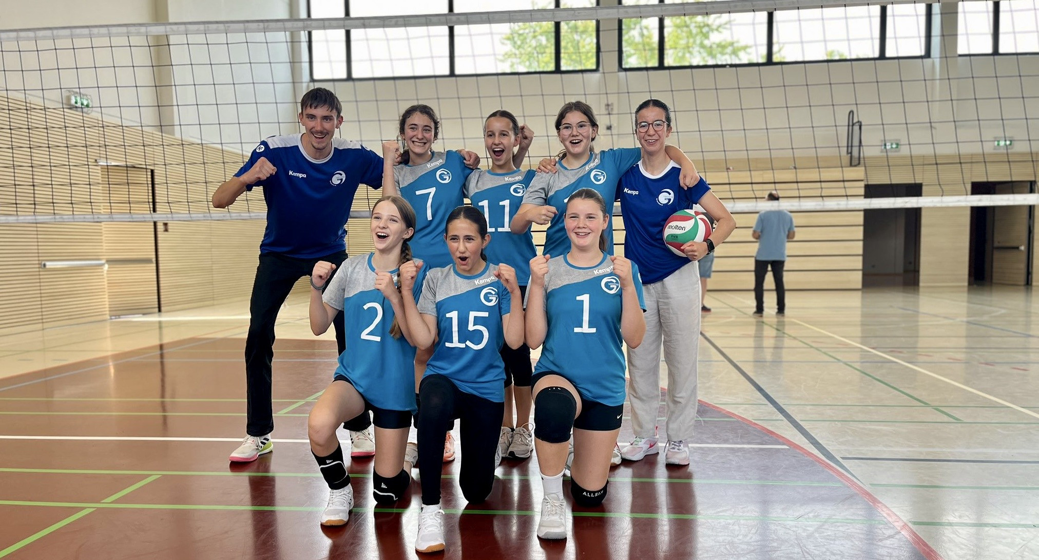 Junges Volleyballteam jubelt gemeinsam in der Sporthalle nach einem erfolgreichen Spiel