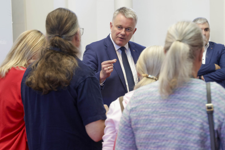 Diskussion in der Staatskanzlei Rheinland-Pfalz mit mehreren Personen, darunter ein Mann im Anzug