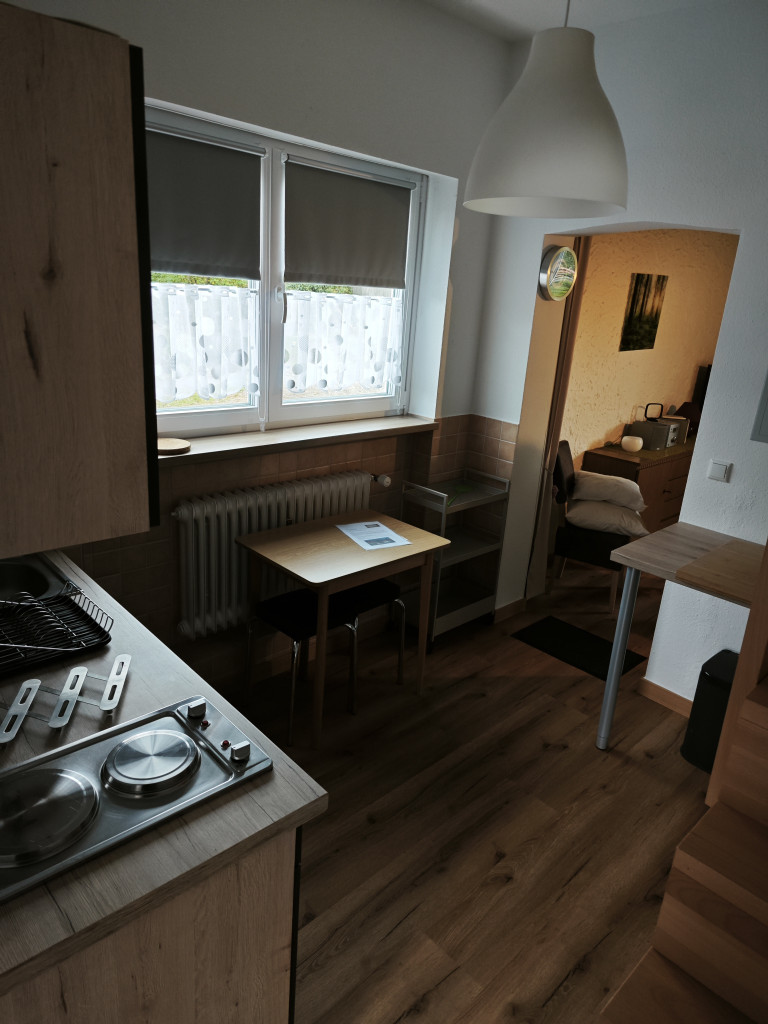Moderne kleine Küche mit Esstisch und Durchgang zum Schlafzimmer, gemütliche Einrichtung Kleine moderne Küche mit Esstisch und Blick ins Schlafzimmer, helle Einrichtung und Holzboden