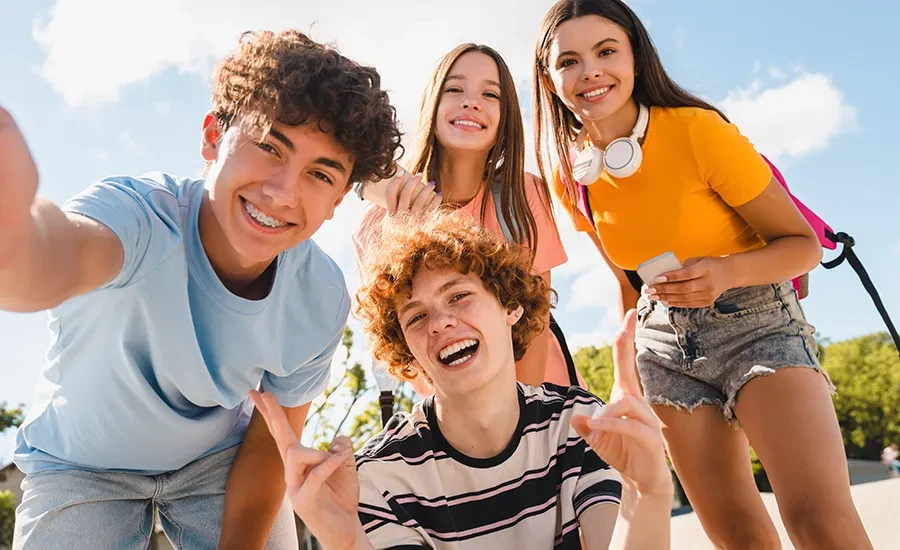 Jugendliche lachen gemeinsam im Freien als Teaserbild für Kieferorthopädie