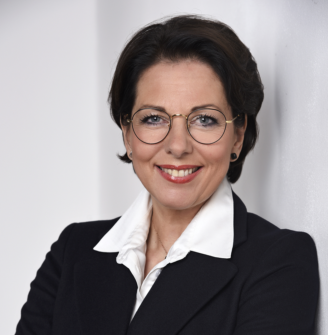 Karin Becker im Business-Outfit vor hellem Hintergrund