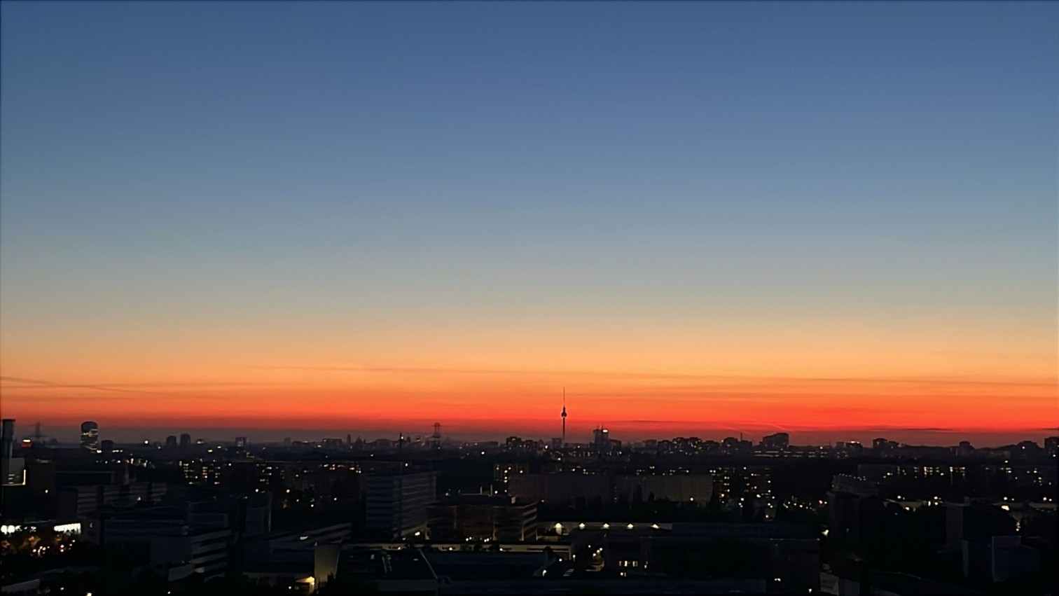Sonnenuntergang über einer Stadt mit leuchtendem Himmel und Silhouette der Gebäude