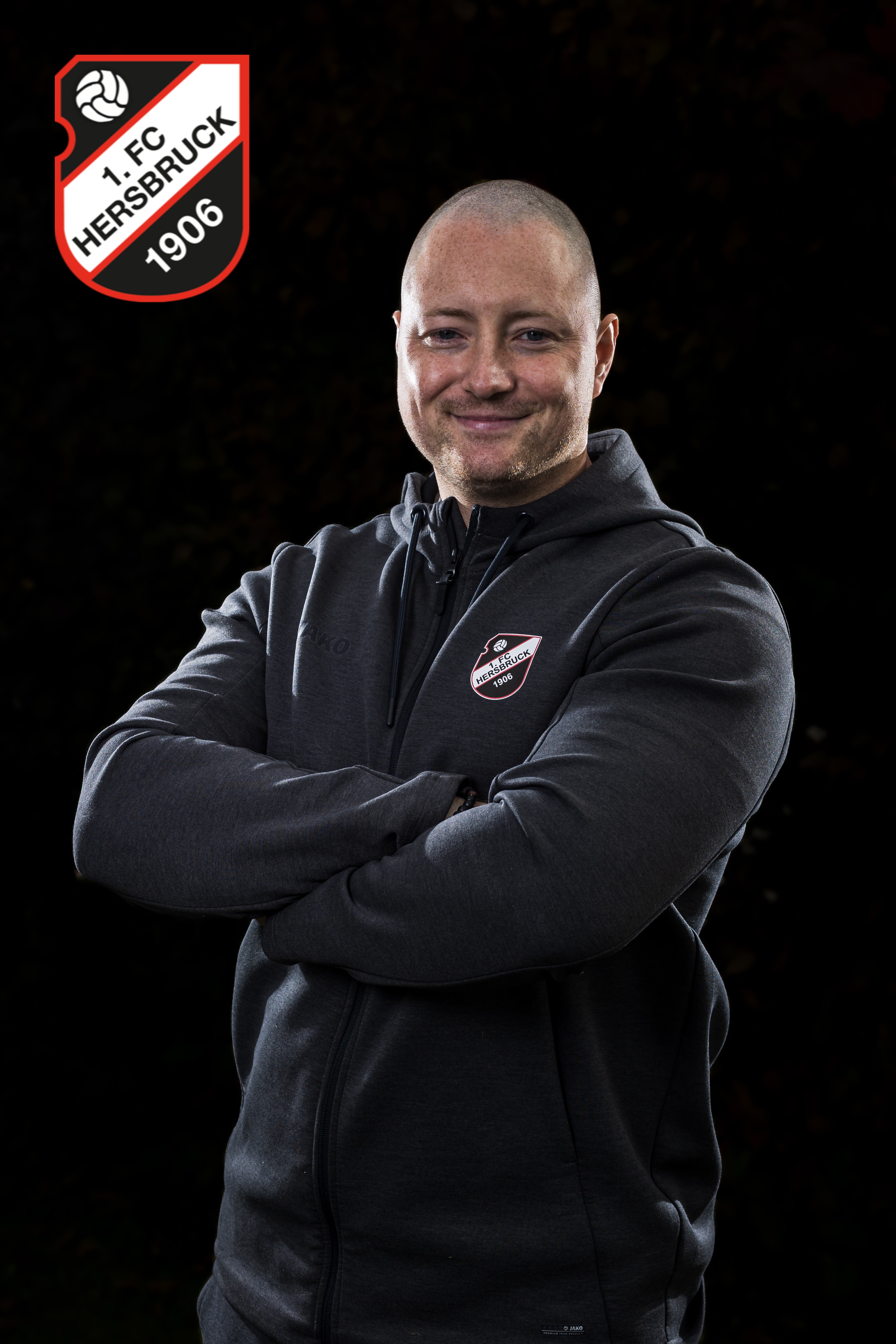 Person mit Sportjacke des Vereins Herzblut 1906 vor dunklem Hintergrund