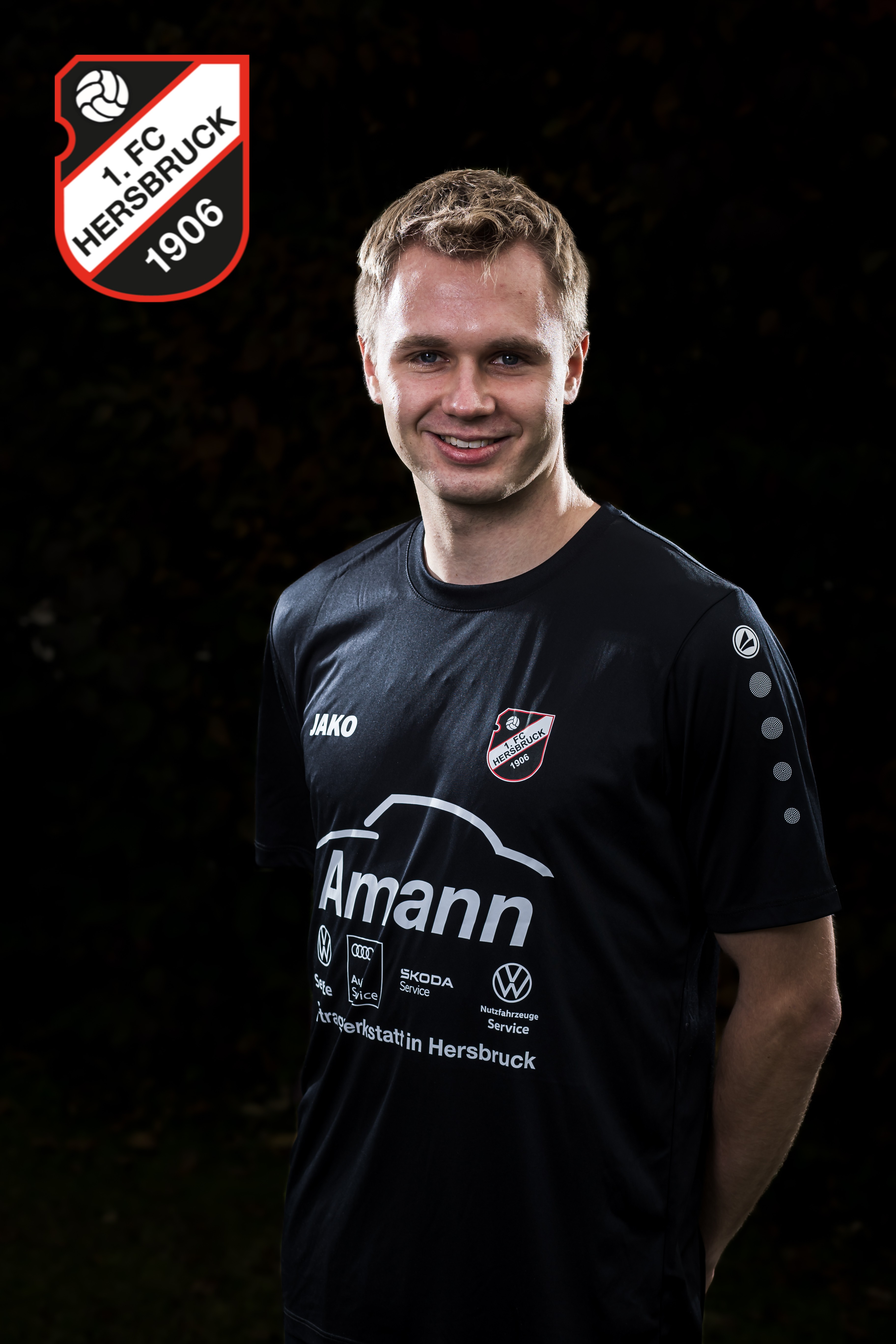 Fußballspieler des 1. FC Hersbruck 1906 im schwarzen Jako-Trikot mit Amann Autohaus Werbung