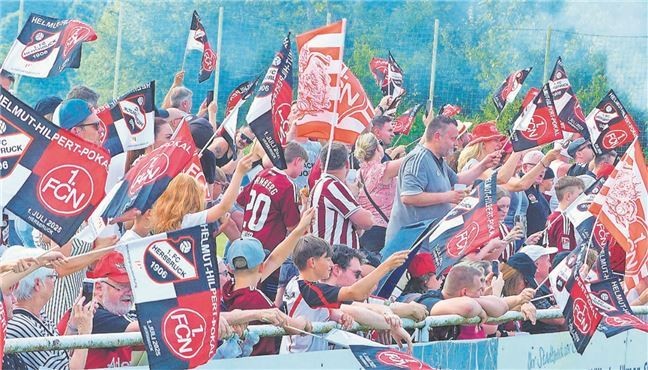 Fußballfans jubeln im Stadion mit Fahnen und Trikots