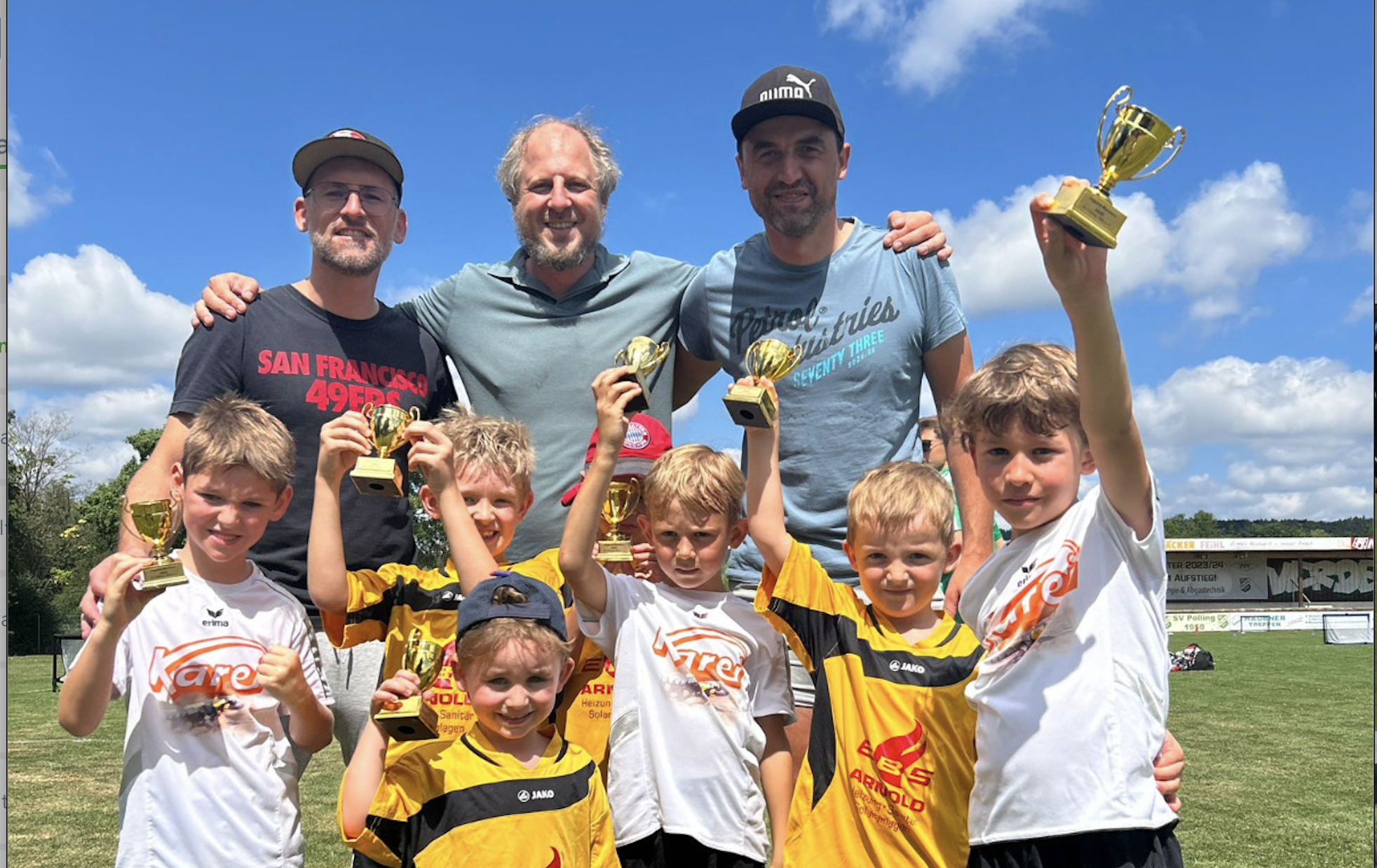 Kinder-Fußballmannschaft mit Trainern hält Pokale nach Turniersieg im Sommer 2025