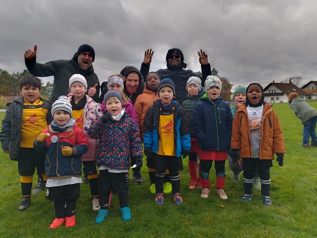 Kinderfußballmannschaft mit Trainern auf einem Fußballfeld im Herbst