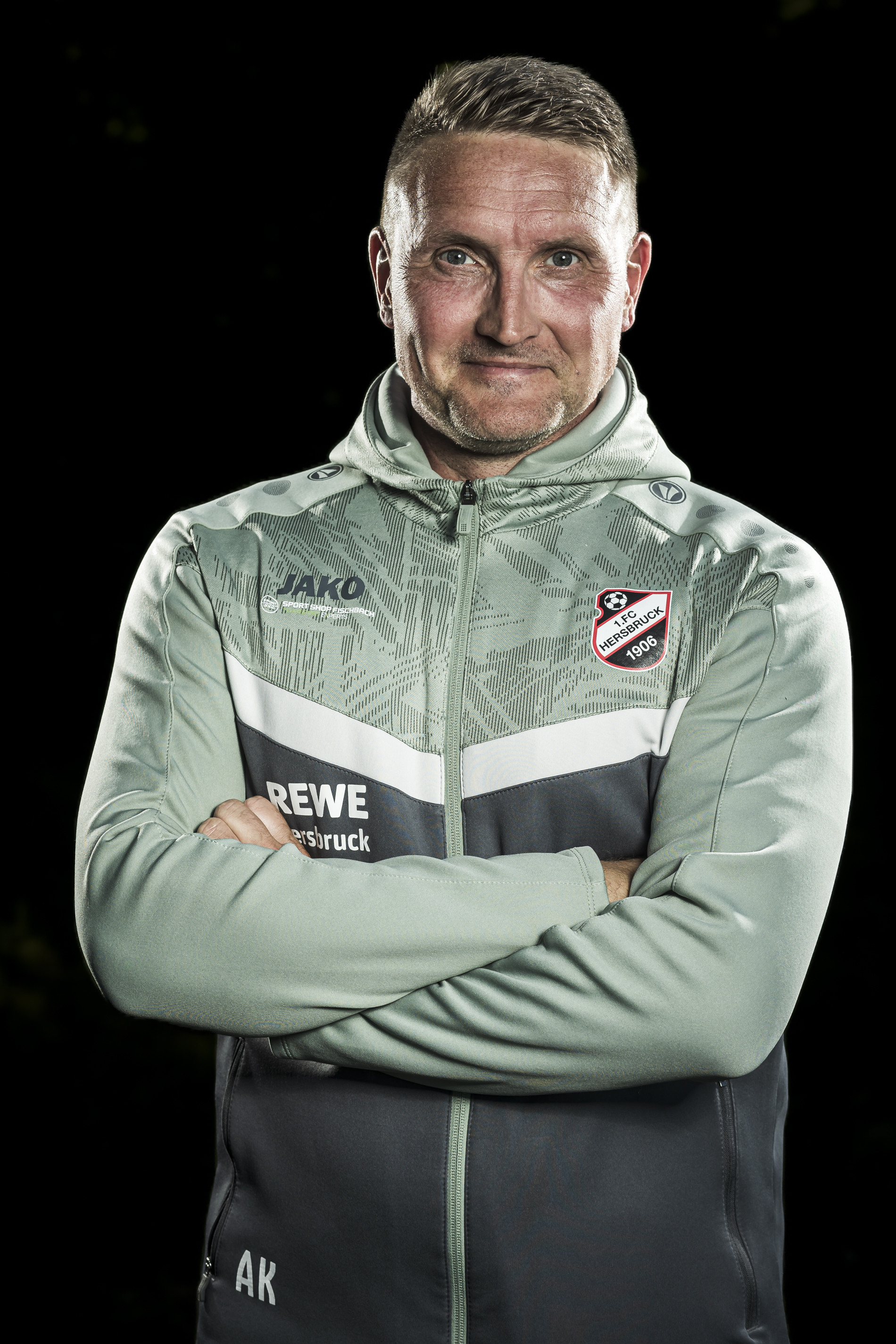 Trainer des 1. FC Hersbruck 1906 in Vereinsjacke vor schwarzem Hintergrund