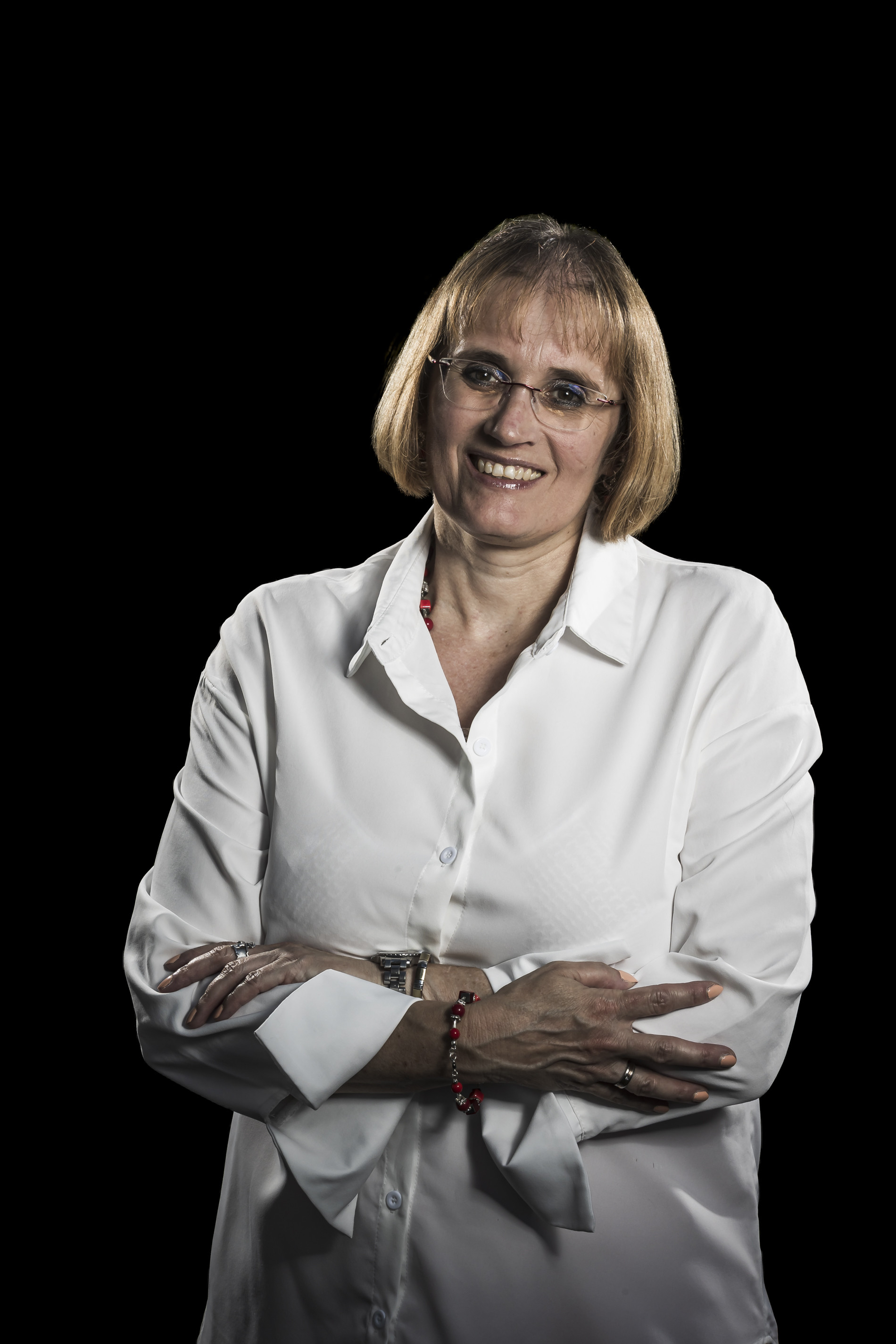 Porträt einer Frau mit Brille und weißer Bluse vor schwarzem Hintergrund
