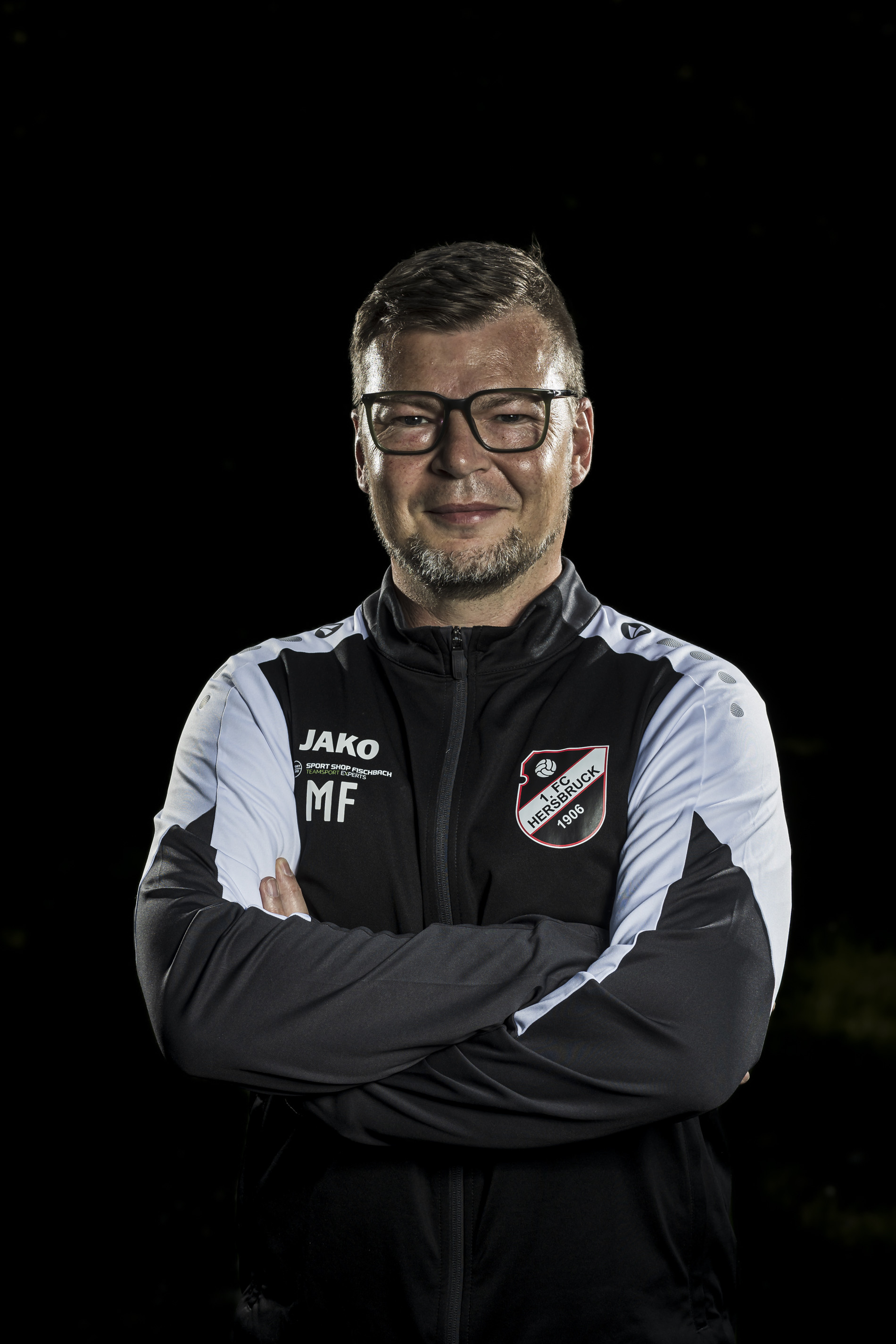 Porträt eines Trainers des 1. FC Hersbruck mit Brille und Trainingsjacke vor schwarzem Hintergrund