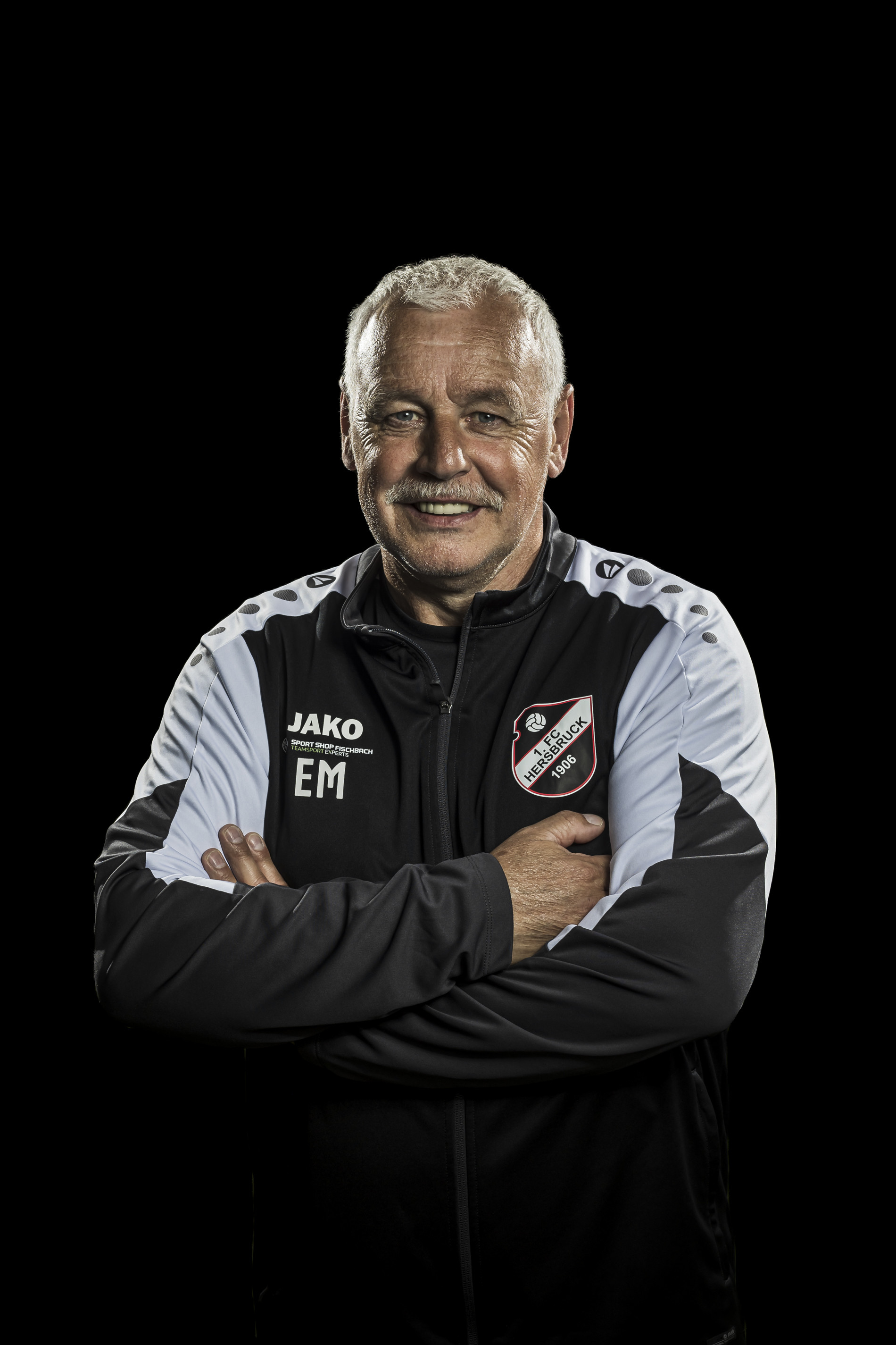 Trainer des 1. FC Heßbruck im Vereinsanzug vor schwarzem Hintergrund