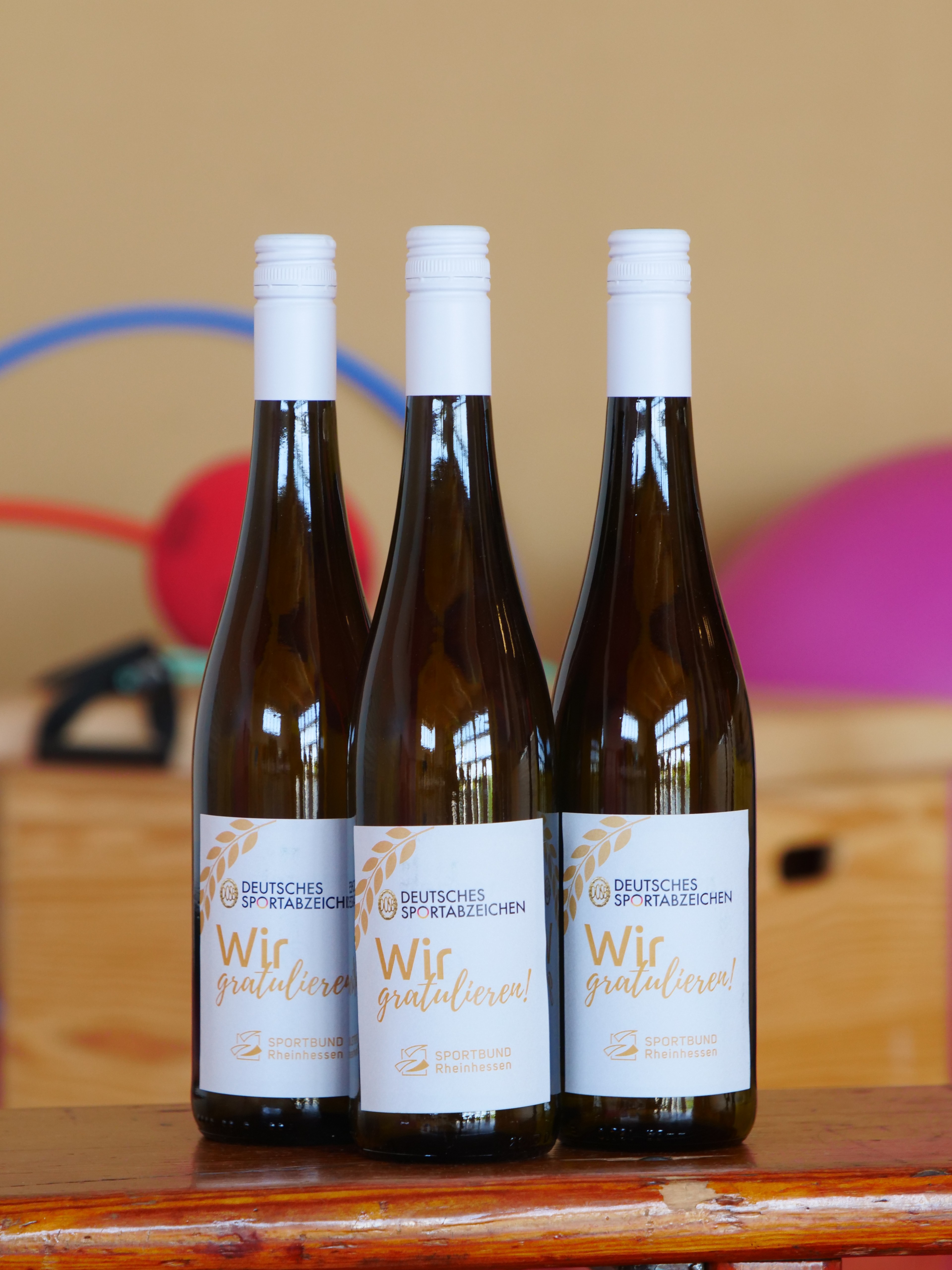 Drei Weinflaschen mit Etikett 'Deutsches Sportabzeichen - Wir gratulieren!'