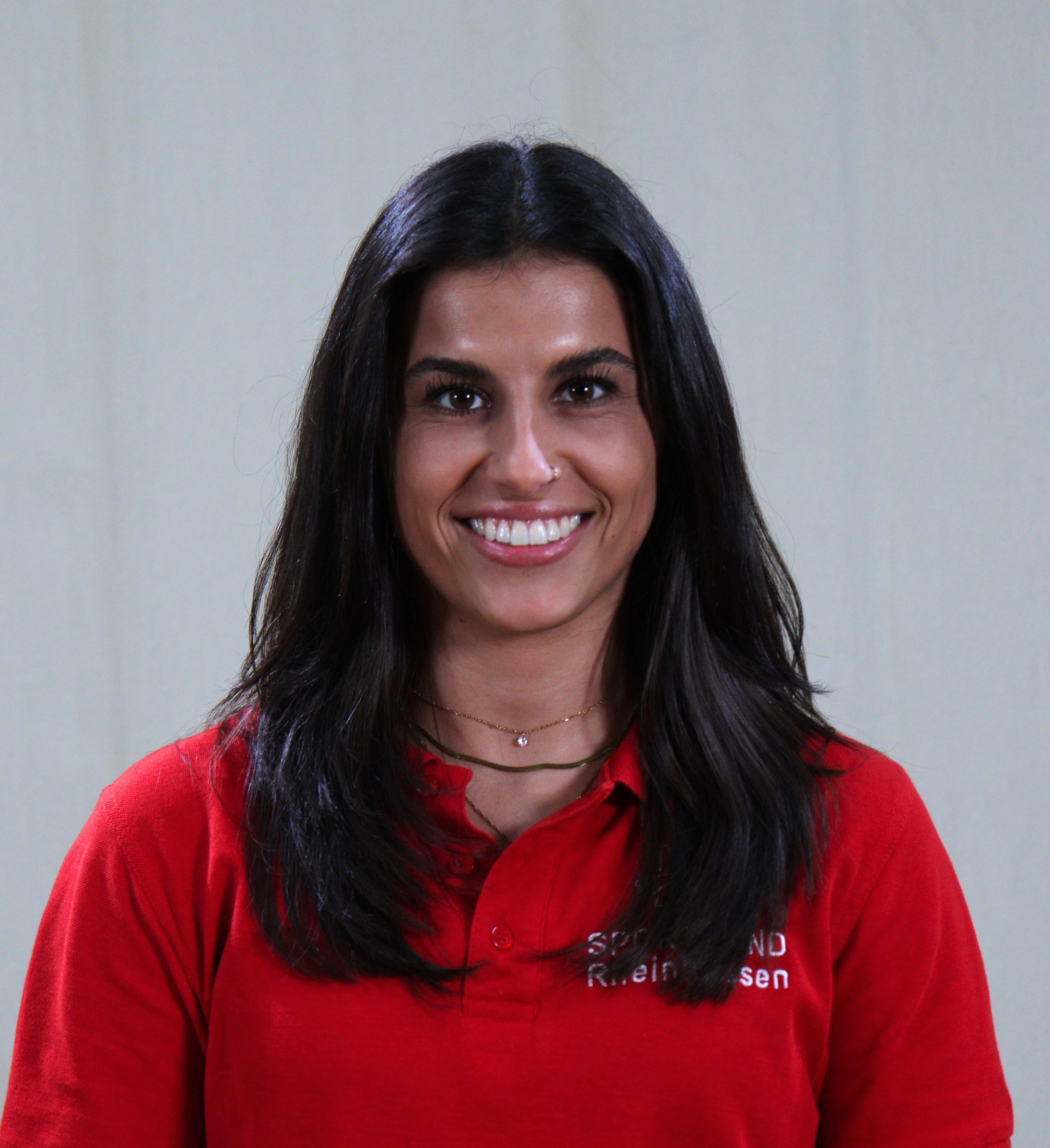 Aurora im roten Shirt mit dunklen Haaren vor hellem Hintergrund